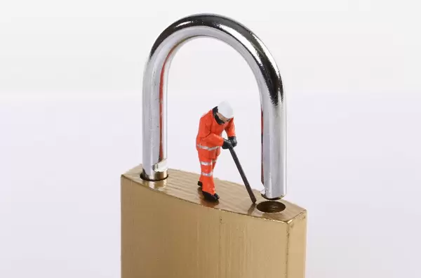 Miniature worker trying to unlock the padlock