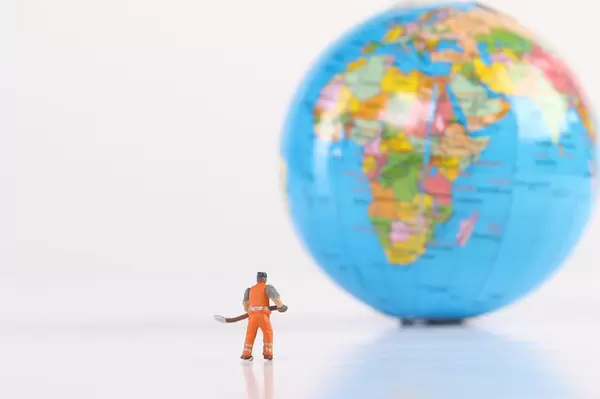 Miniature worker with globe on white background