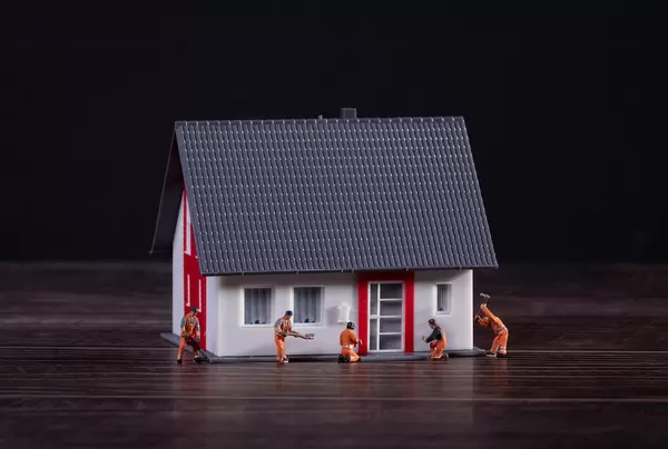 Miniature workers building a house