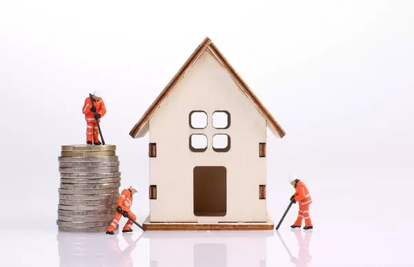 Miniature workers building a wooden house