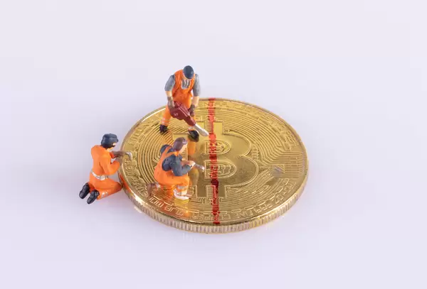 Miniature workers cutting Bitcoin. Halving concept