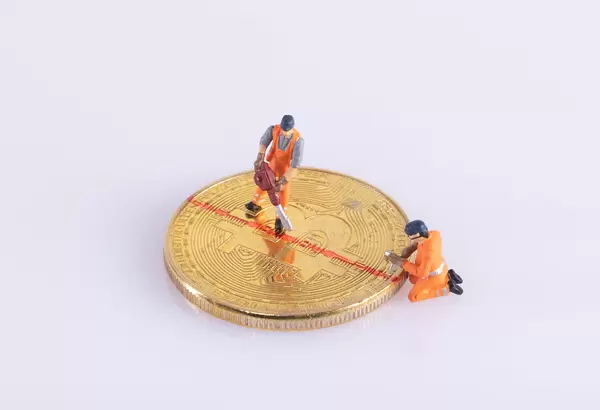 Miniature workers cutting Bitcoin