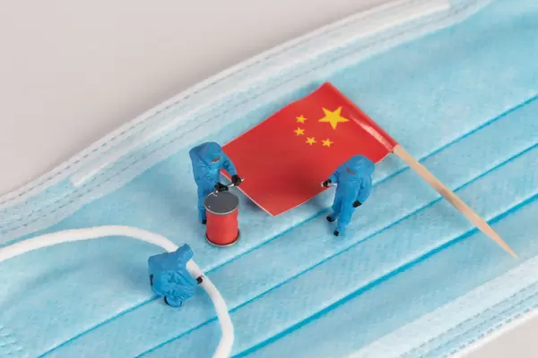 Miniature workers in protective clothes on a medical mask with flag of China