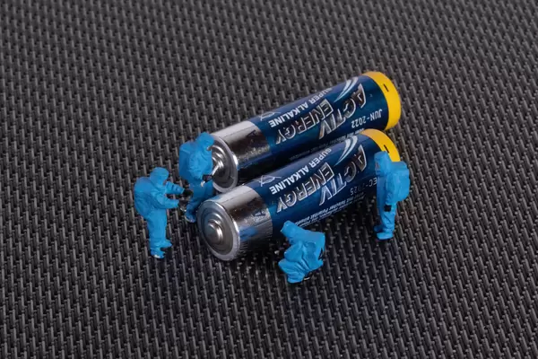 Miniature workers in protective clothes with a battery