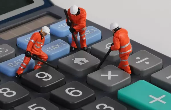 Miniature workers repairing home button on calculator
