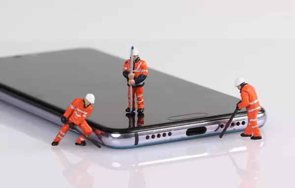 Miniature workers repairing smartphone