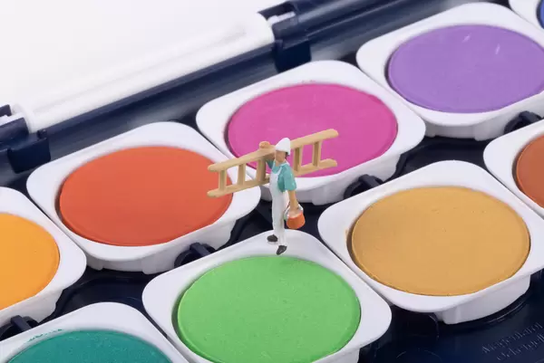 Miniature workers standing on a green paint color