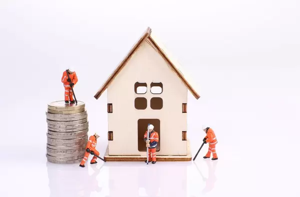 Miniature workers team build a wooden house