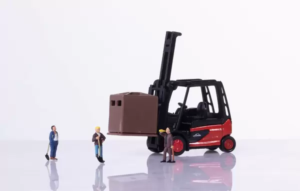 Miniature workers with forklift on white background