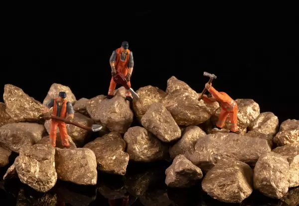 Miniature workers with gold nuggets