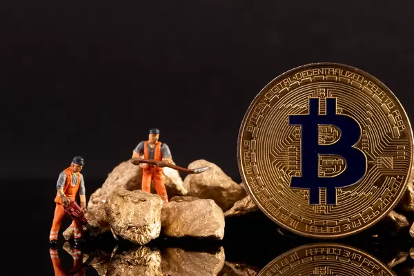 Miniature workers with golden Bitcoin and gold nuggets on black background
