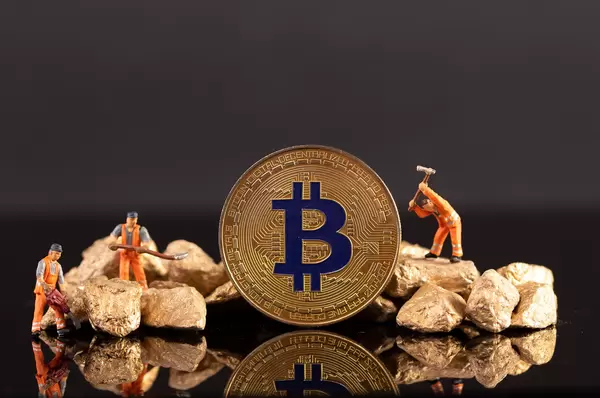 Miniature workers with golden Bitcoin and gold nuggets