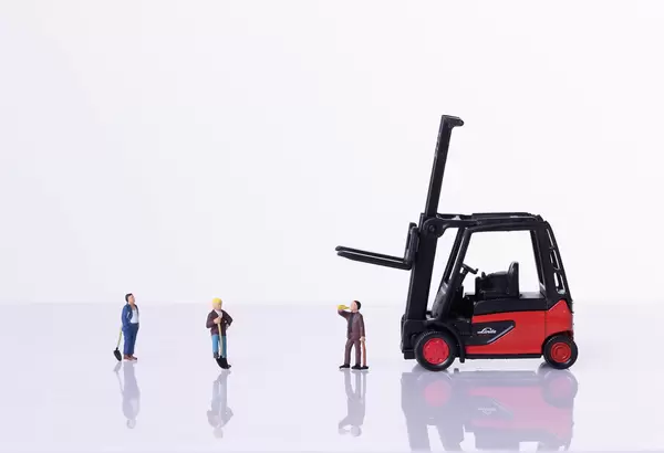 Miniature workers with red forklift on white background