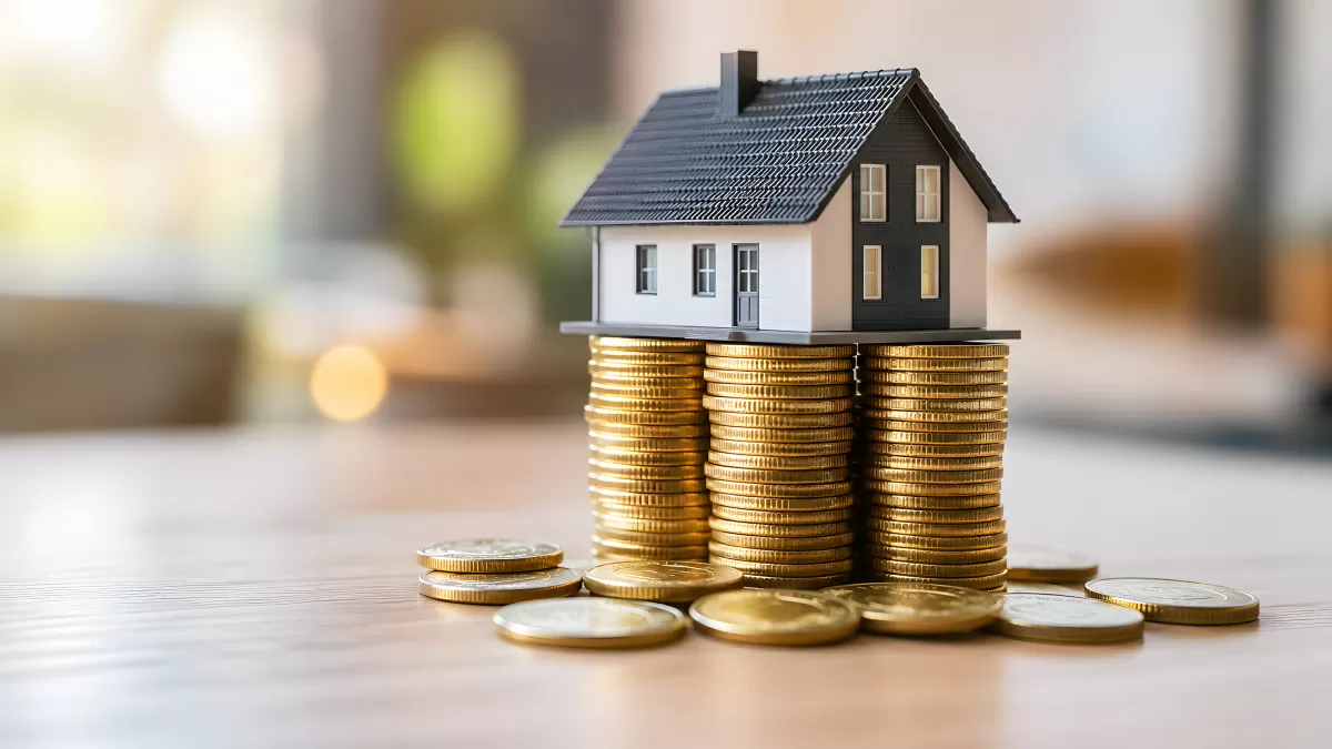 Miniaturhaus auf Goldmünzstapeln als Immobiliensymbol