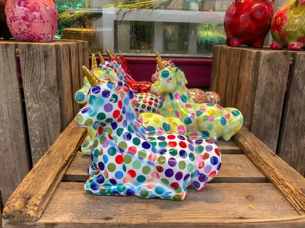 Mit bunten Punkten bemalte Einhörner aus Porzellan auf Holzgestell