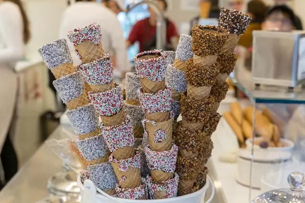 Mit bunten Streuseln, Nüssen und Kokosraspeln verzierte Eiswaffeln in einem Café in Barcelona, Spanien