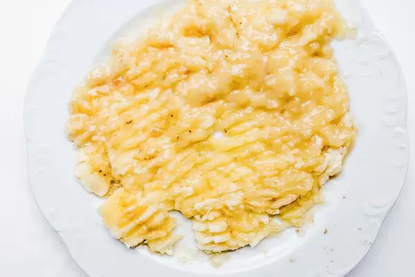 Mit Gabel zerdrückte Bananen auf weißem Teller