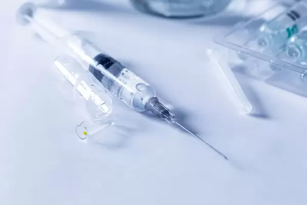 Mit Medizin gefüllte Spritze  neben leerer Ampulle und noch neuen Arzneifläschchen