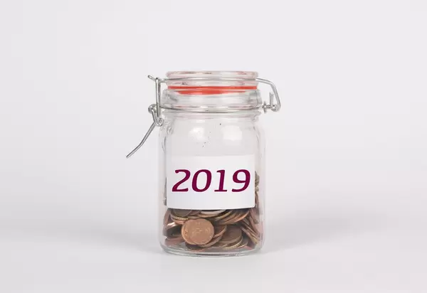 Mit Münzen gefülltes Glas mit Aufschrift 2019 symbolisiert Sparen für 2019