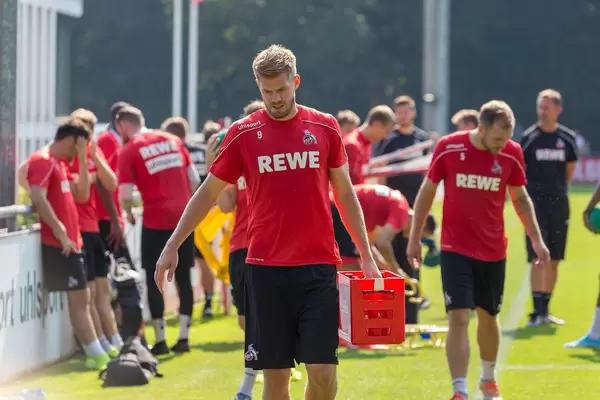 Mittelstürmer Simon Terodde trägt einen kleinen Coca Cola Kasten nach dem Fußballtraining vom Platz