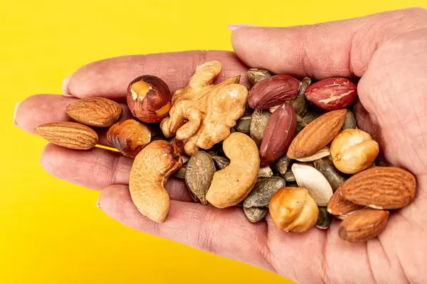 Mix nuts and seeds in a female hand on a yellow background (Flip 2020)