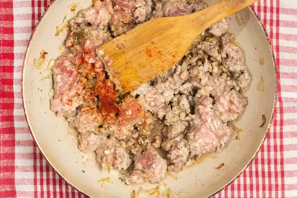 Mixing minced meat with paprika pepper and salt