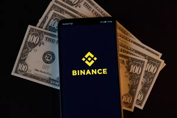 Mobile phone and Binance logo on dollars
