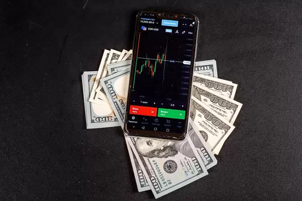 Mobile phone with a trader program on the screen with cash on a black background