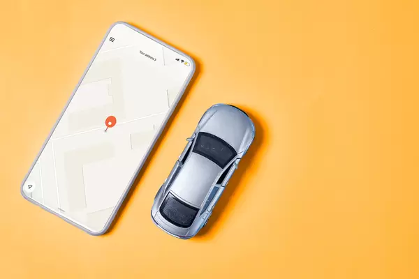 Mobile phone with opened map application and car toy on yellow background