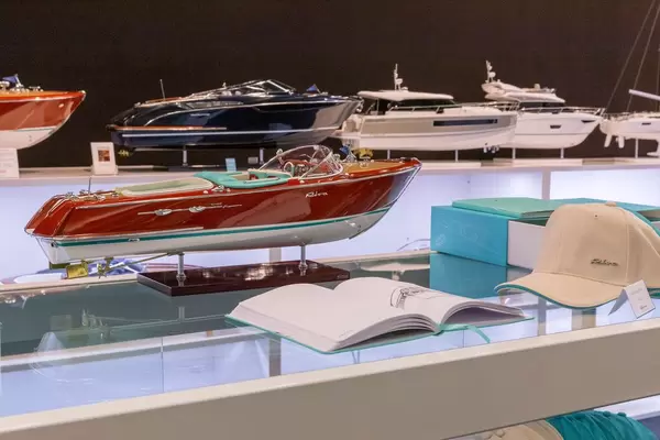 Modell eines luxuriösen Motorboots auf Tisch mit Erklärungsbuch und passendem Hut an Messe