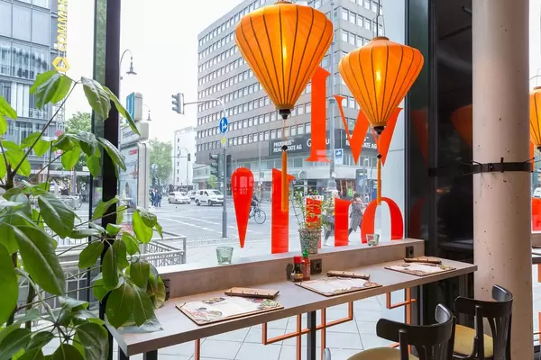 Modern colourful intérieur of the coa Wok & Bowl restaurant in Cologne with plants and seats overlooking the street