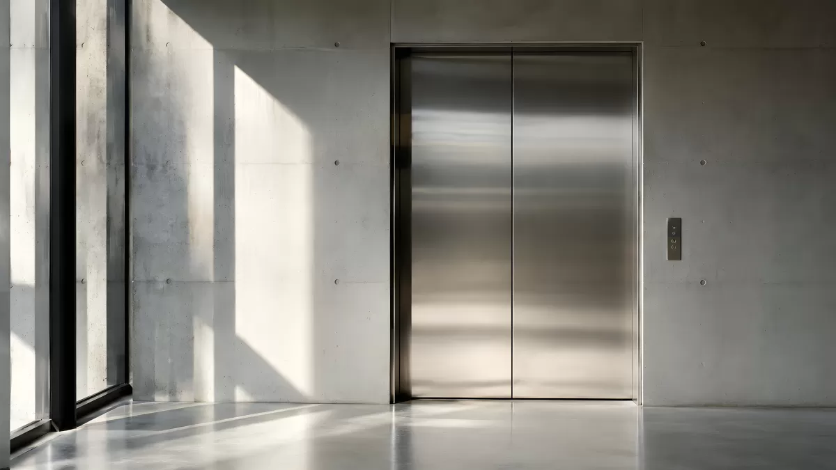 Moderner Aufzug mit Edelstahltüren in Betonhalle