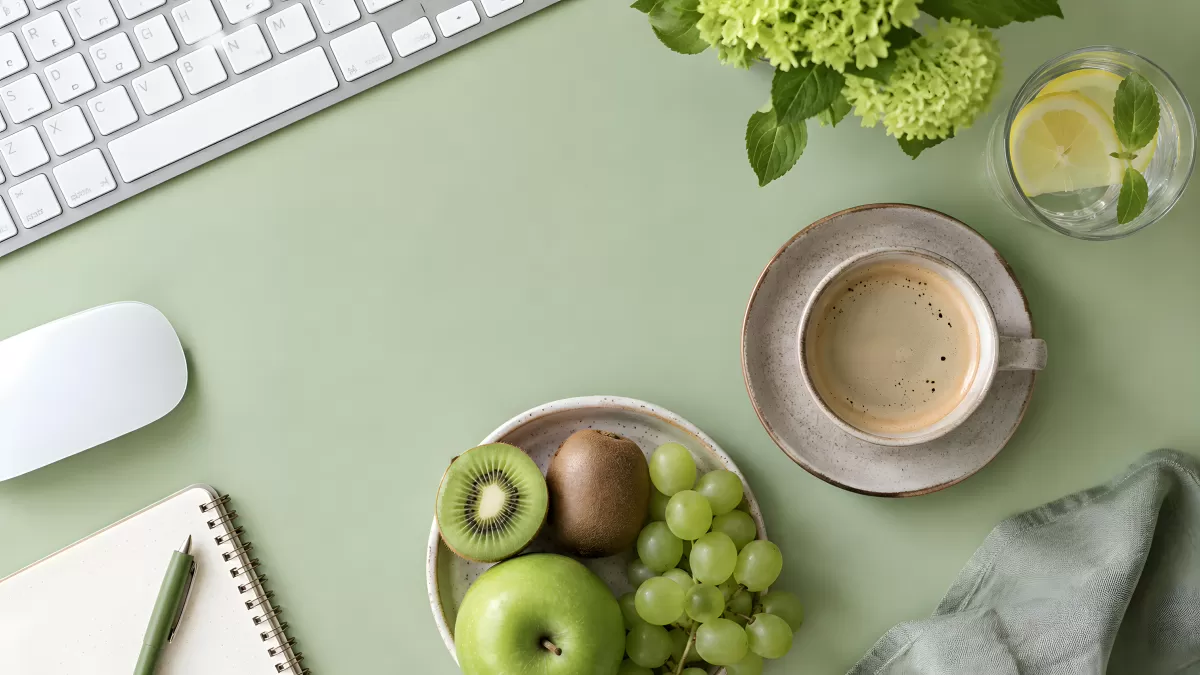 Moderner Schreibtisch mit Obst, Kaffee und Notizbuch