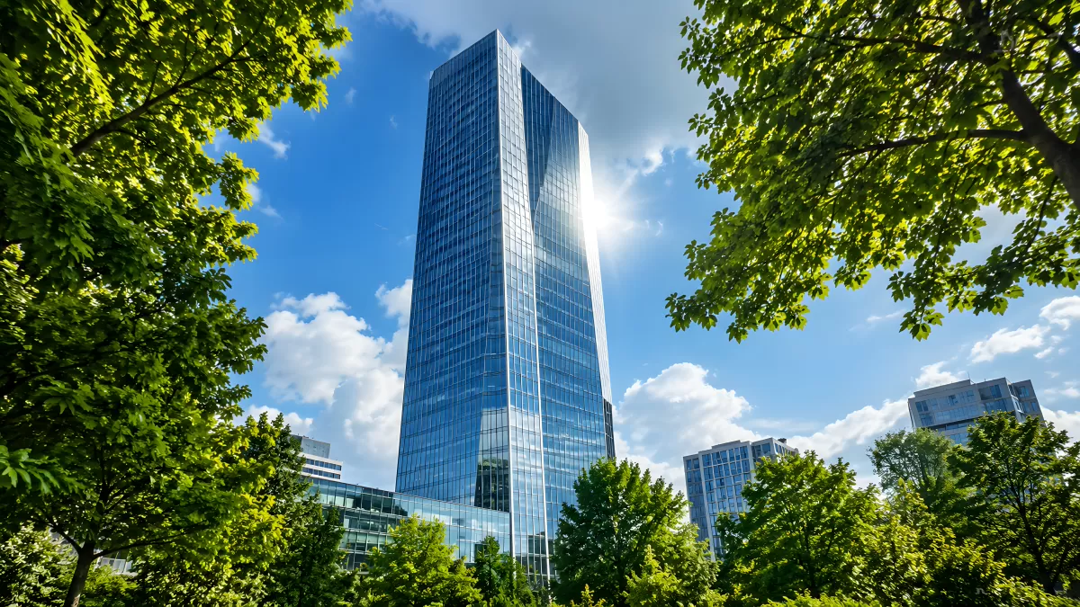 Modernes Hochhaus aus Glas zwischen grünen Bäumen