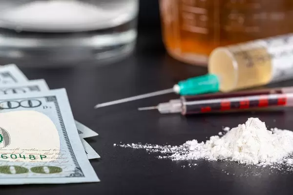 Money and drug in powder and solution with syringes