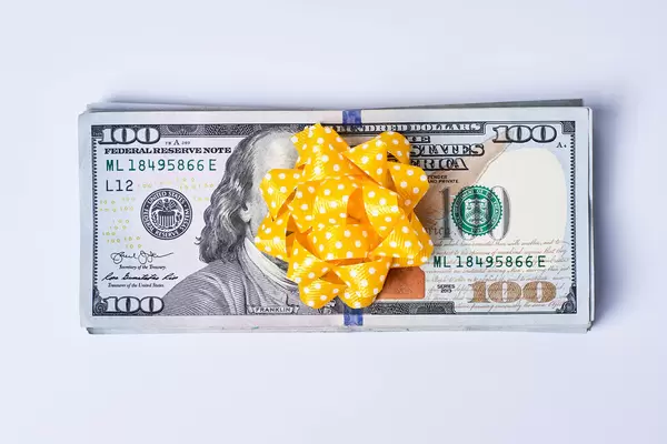 Money gift - Pile US dollar banknotes wrapped with bright yellow ribbon