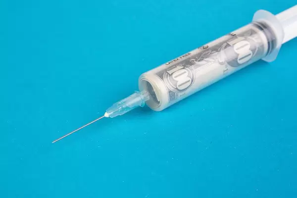 Money in syringe on blue background