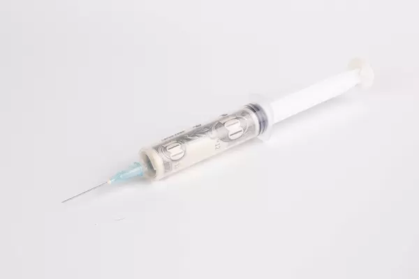 Money in syringe on white background