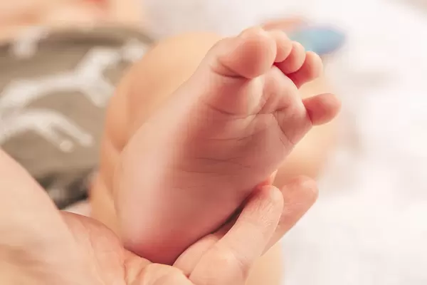 Mother's caring hand holding her little baby's feet with love
