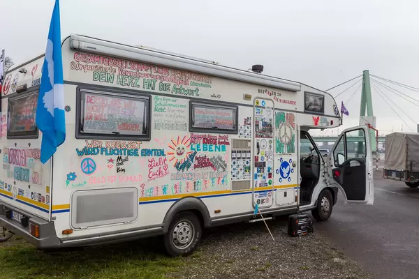 Motorhome with many peace quotes and a blue flag with a white dove at Coronavirus protest in Cologne
