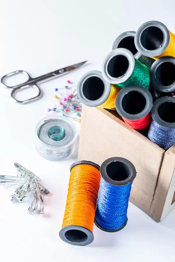 Mountain of colorful threads in a box on the table with needles, pins and scissors with measuring tape
