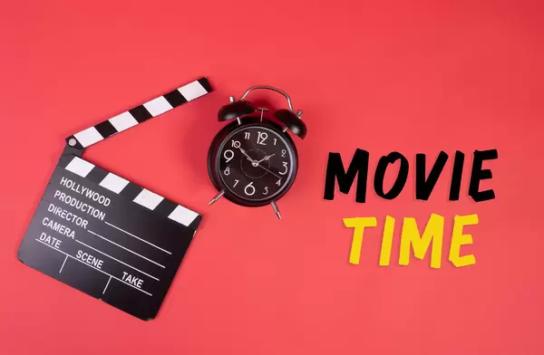 Movie clapper, alarm clock and Movie Time text on red background