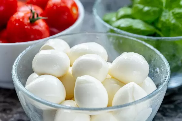 Mozzarella cheese, red cherry tomatoes and fresh Basil leaves in bowls on the table (Flip 2019) (Flip 2019)
