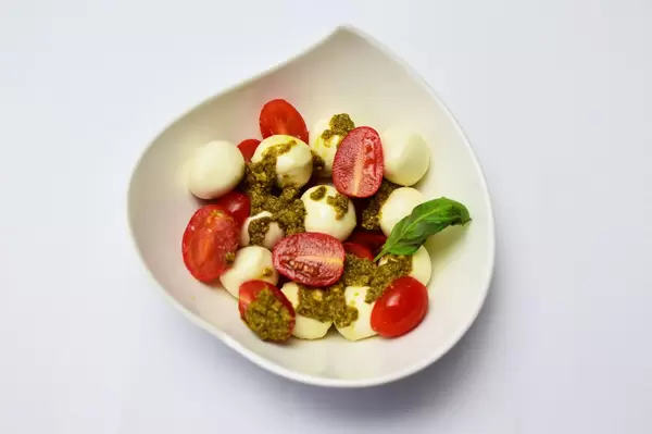 Mozzarella mit Kirschtomaten, Pesto und Basilikum in einer stilvollen Schale