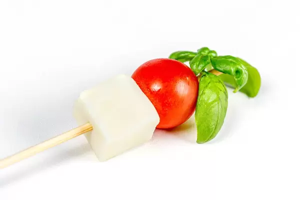 Mozzarella, red cherry tomato and basil leaves on a wooden stick