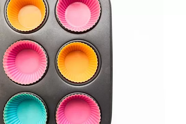 Muffin-Backform aus Metall ausgestattet mit sechs bunten Muffin-Backförmchen aus Silikon