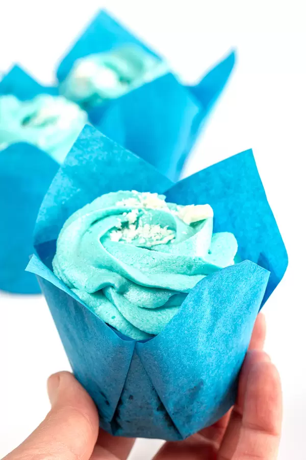 Muffin with blue cream in hand, close-up