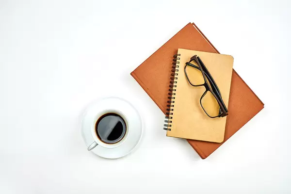 Mug of coffee and two notepads on white background