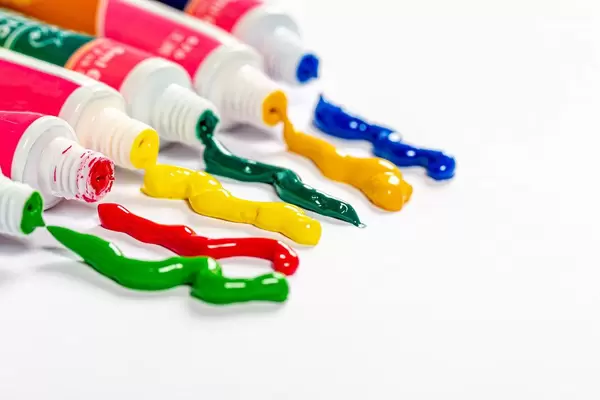 Multi-colored paint coming out of the tube on white background