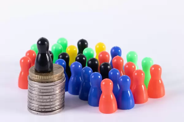 Multi colored pawn figures and one black on the coin stack